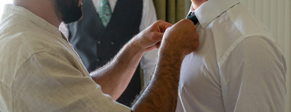 Groom Getting Ready with Best Man Adjusting Tie Before Wedding