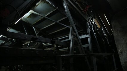 Powerful, massive industrial conveyor system operates in a dark, abandoned underground facility. Heavy metal framework, moving chains, and gears transport materials in this dirty, functional, and agin - Powered by Adobe