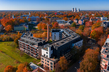 Midday aerial shows a U shaped residential complex around a brick smokestack in Riga, Latvia, with...