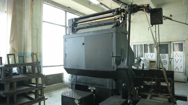 Interior view of an abandoned industrial bunker's machinery room. Features large mechanical equipment, concrete structures, and a long row of heavy electrical switchgear control panels.