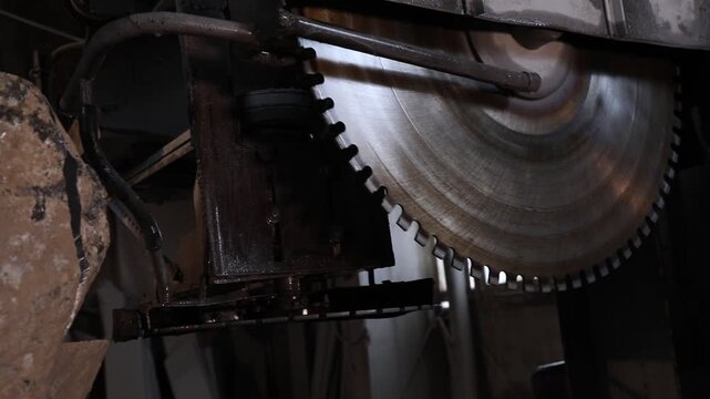 Close-up of a large diamond saw cutting a natural stone block in a factory. Water cools the blade and suppresses dust during the industrial marble or granite processing.

