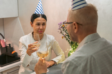 Couple Champagne Toast Party Hats; Indoor Birthday Celebration; intimate romantic moment during a...