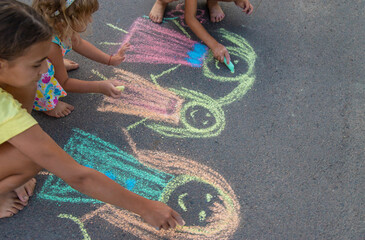 Children draw with chalk on the asphalt. Selective focus.