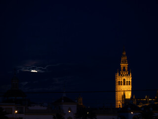 Fototapeta premium Seville, Spain - February 24, 2024. The Giralda Tower of Seville illuminated under the moonlight on an Andalusian night