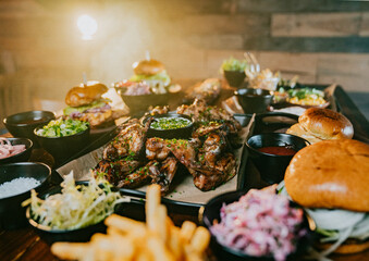 A table full of food including a plate of wings, a plate of fries