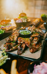 A plate of chicken wings is on a table with other food items