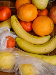 Freshly bought oranges, bananas, and apples piled on a wooden table with plastic bags &mdash; vibrant, healthy fruit still life perfect for nutrition, grocery, or lifestyle themes.