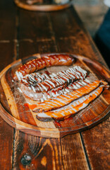 A plate of food with a variety of meats and sauces on a wooden table