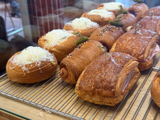 Assorted croissants and pastries with cheese and ham. Savory flavor, texture, and artisanal baking in modern cafe display.
