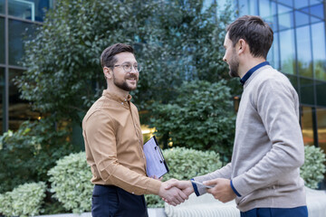 Two smiling men building a professional relationship and making a business deal, shaking hands with...