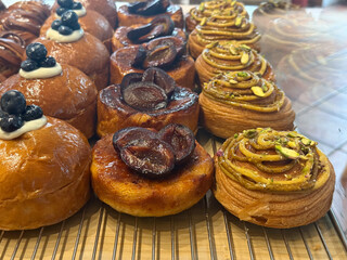 Assorted pastries with blueberries, plums, and pistachios in bakery display. Sweetness, texture, and craftsmanship in artisanal dessert presentation.