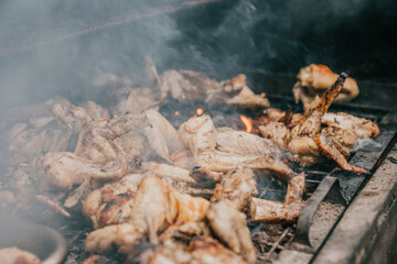 A grill full of chicken wings is smoking and cooking