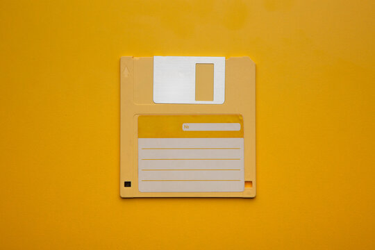 Orange-yellow 3.5-inch floppy disk centered on a solid yellow back