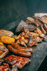 A variety of meats and vegetables are being cooked on a grill