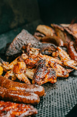 A plate of food with chicken wings, sausages, and other meats