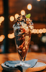 A chocolate sundae in a glass with whipped cream and chocolate sauce on top