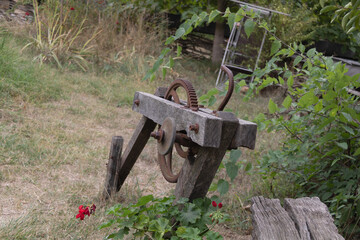 Old wooden and metal mechanical gear structure from traditional farm equipment surrounded by grass and plants in countryside