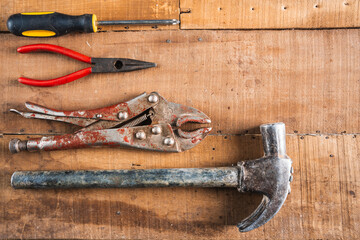 Antique construction tools, such as an old wooden level, a wooden plane, pliers, and a plumb line, are isolated and display an antique charm on a brown wooden wall.