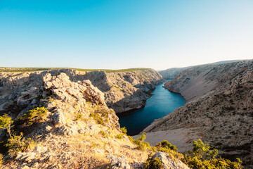 View of the Zrmanja River Canyon in Croatia, with winding turquoise waters cutting through limestone cliffs. A scenic natural wonder popular for kayaking and hiking