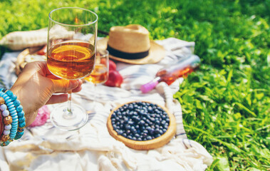 Wine in hands of woman at picnic. Selective focus.