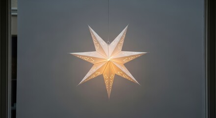 Illuminated white paper star lantern hanging in front of window