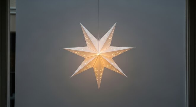 Illuminated white paper star lantern hanging in front of window