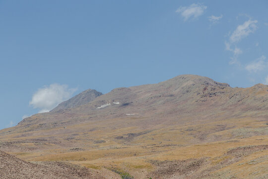View of rugged mountains rise against the sky, the dry landscape painted in earthy tones, with sparse vegetation dotting the terrain, Lake Kari, Shirak Province, Armenia.