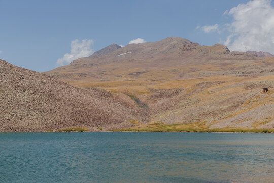 View of the serene lake reflecting the warm tones of the rocky, arid mountains under a clear blue sky, a tranquil scene, Lake Kari, Shirak Province, Armenia.