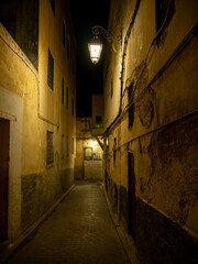 Fototapeta premium A small dark residential street in the medina of Fes, at night