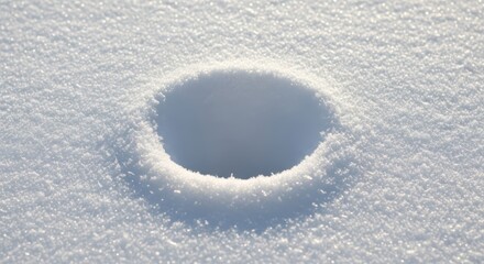 Close-up of circular snow hole in sunlit snow surface