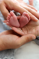 Gentle adult hands hold tiny baby feet, symbol of care, love, and family warmth.
