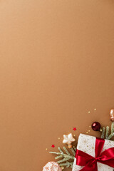 Christmas composition with white gift box, red ribbon, baubles, candy cane, pine branches, and...
