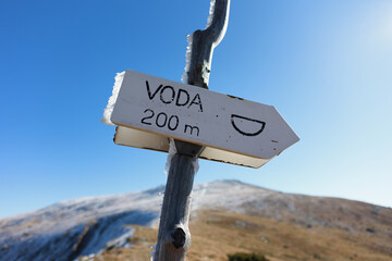 Sign, placard, guidepost with Czech and Slovak text Voda, translation Water.  Well and spring - arrow showing direction to natural source of drinking and potable water in the nature. Shallow focus.