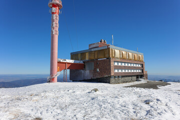 Building of television and communications tower and transmitter, Kralova hola, Low Tatras, Slovakia. Utility architecture on the top of mountain. Winter with snow and clear blue sky. 