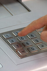 A person who uses their hand to enter their card PIN to withdraw money from an ATM.