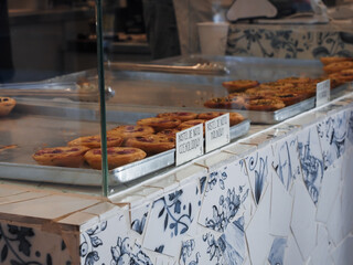 Poznan Poland - 19.10.2025: Display of Portuguese pastel de nata custard tarts behind glass counter in local cafe bakery