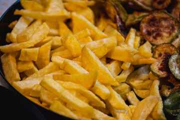Fried potato wedges and French fries in a bowl and pan