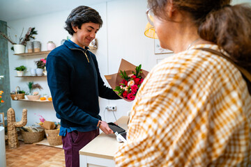 Florist handing flower bouquet to customer using contactless payment