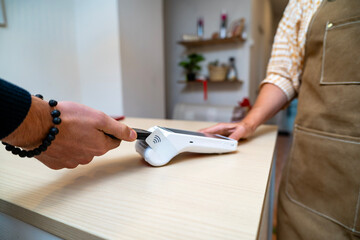 Customer making smartphone contactless payment at pos terminal