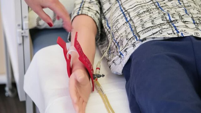 A female medical professional attaches electrocardiogram electrode clips to the arm of a pediatric cardiac monitoring mannequin in a medical institute, close-up