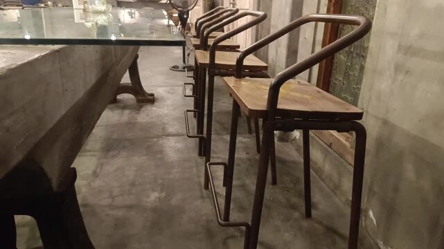 A slow, smooth pan reveals an elegantly arranged bar or cafe space. Focus is on the minimalist design, showcasing the wood chairs, table, metal