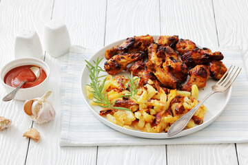 bbq chicken wings with fried potatoes on plate