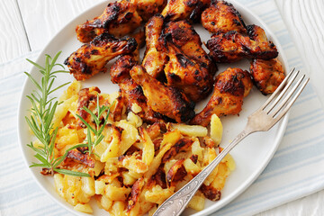 bbq chicken wings with fried potatoes on plate