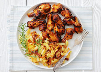 bbq chicken wings with fried potatoes on plate