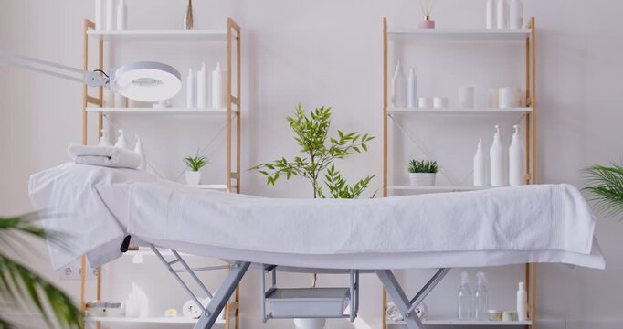 Interior of light empty couch with cosmetology lamp in beauty spa salon ready to accept client for treatment procedure or massage therapy. Wellness and beauty day concept. 4k video. Slow motion video