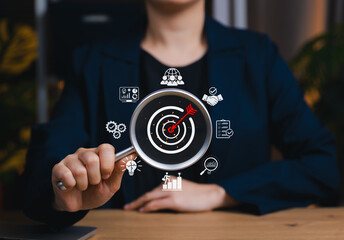 Business goals and target achievement concept. Magnifying glass focused on target with marketing...