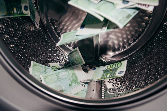 Hundred-euro banknotes scattered inside steel drum of a washing machine, act of money laundering