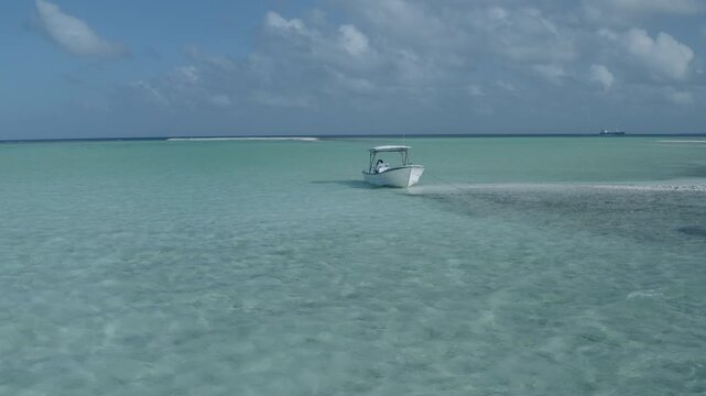 A shallow-draft skiff speeds across the crystal-clear flats of Kiritimati (Christmas Island), Kiribati, en route to world-renowned saltwater fly fishing grounds. The remote Pacific atoll is famous for