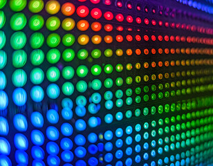A close-up view of a vibrant LED display with numerous illuminated dots transitioning through the colors of the rainbow.