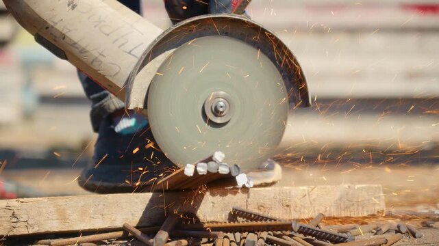 Worker cutting rebar bars with an angle grinder at a construction site